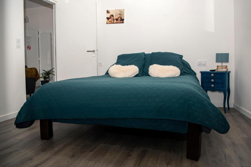 ein Schlafzimmer mit einem grünen Bett mit zwei Kissen in der Unterkunft Cottage tout confort neuf au calme 6p WiFi in Chaumes en Retz