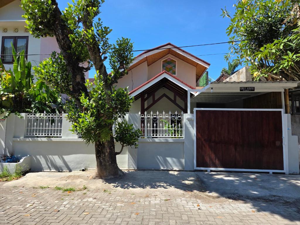 una casa blanca con una puerta y un árbol en Greyhouse, en Senggigi 