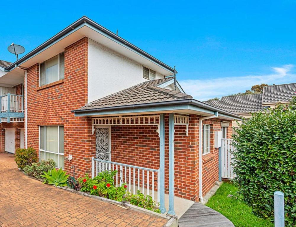 a red brick house with a white fence at Townhouse in Shellharbour Village in Shellharbour