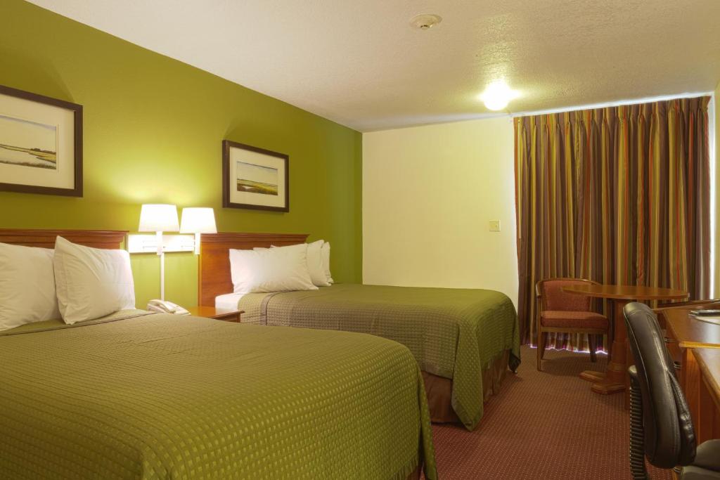 ein Hotelzimmer mit 2 Betten und grünen Wänden in der Unterkunft Marina Inn & Suites Chalmette-New Orleans in Chalmette