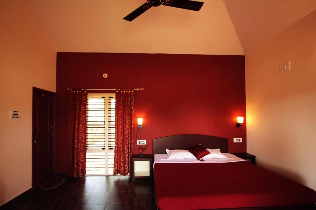 a bedroom with a bed with a red wall at Dandeli Chalet in Dandeli