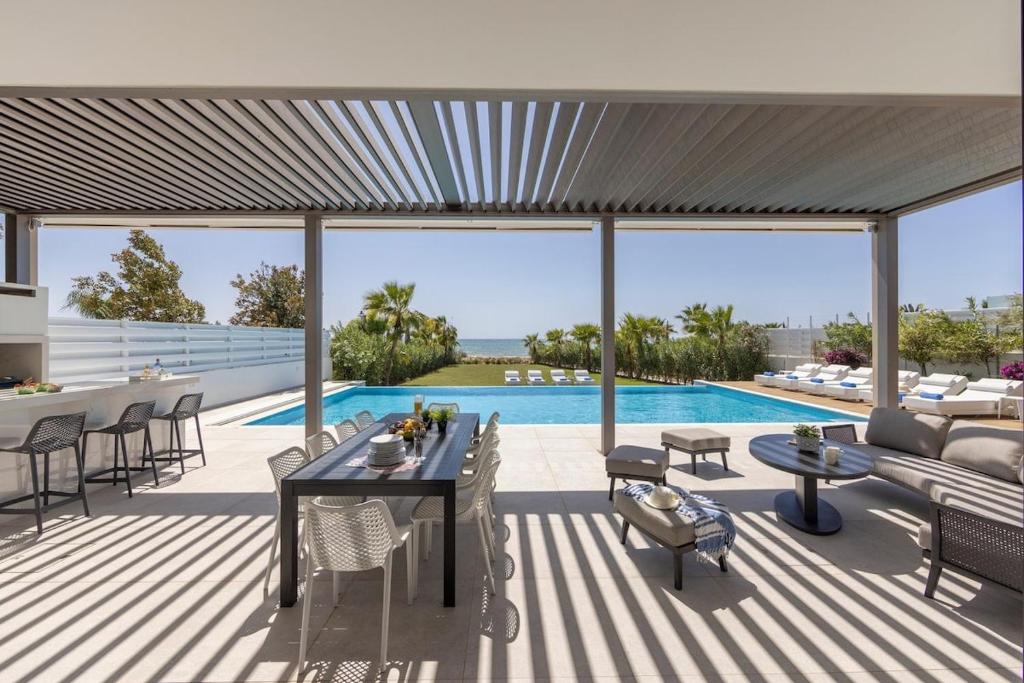 a patio with a table and chairs and a pool at Villa JoJo Seafront in Ayia Napa