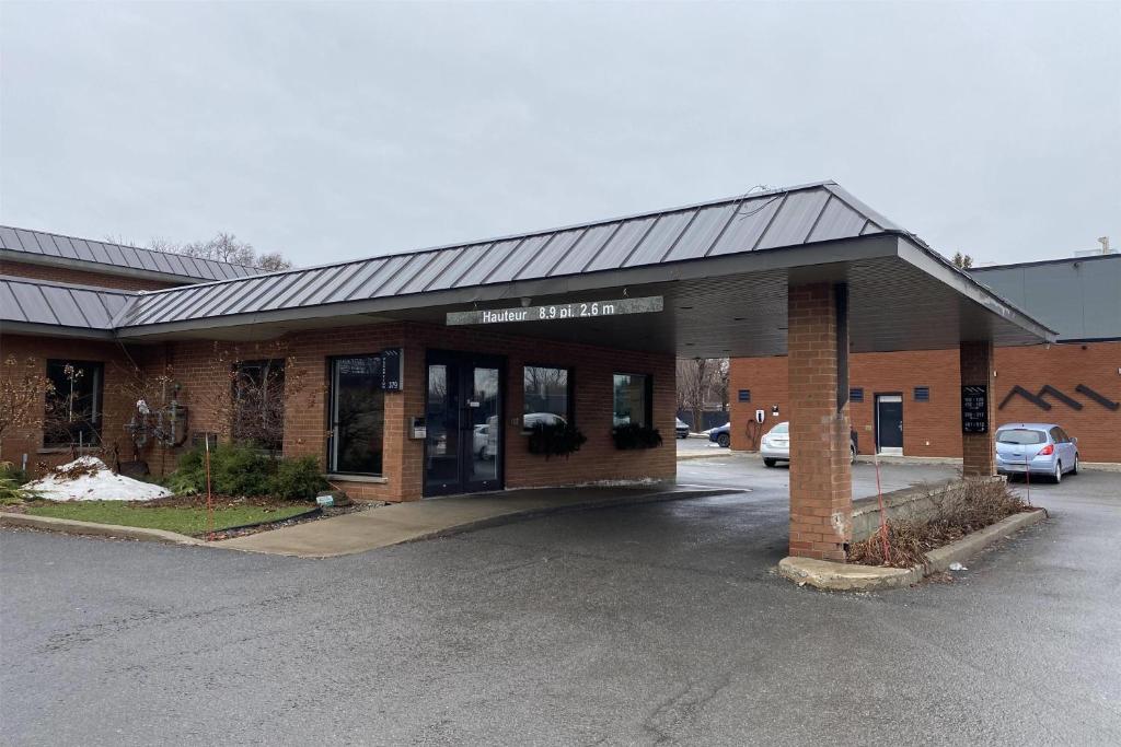 a store front of a brick building with a parking lot at Ramada by Wyndham Laval in Laval