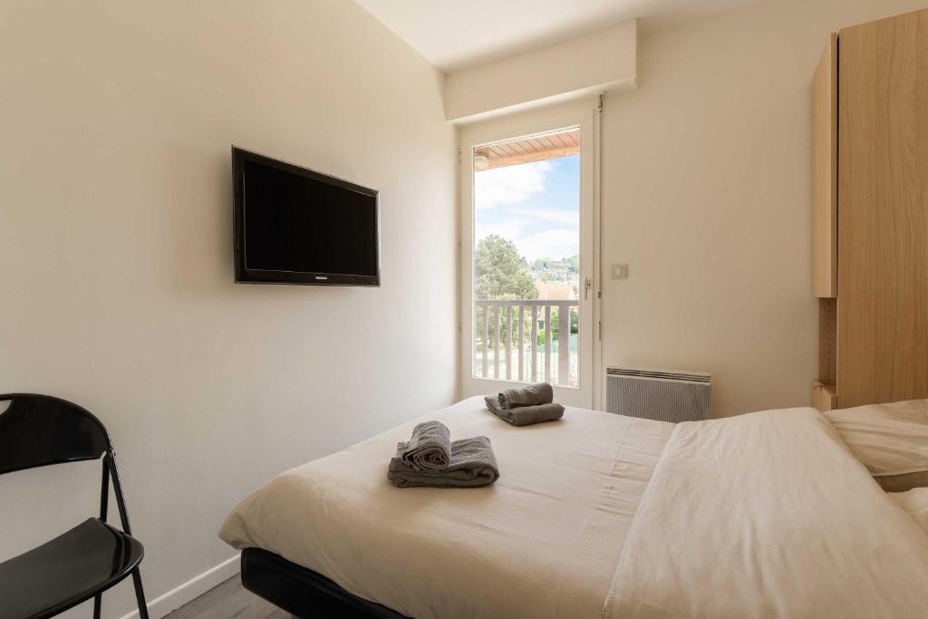 une chambre avec un lit avec une télévision au mur dans l'établissement Stunning 2-bedroom accommodation - pool and tennis, à Deauville