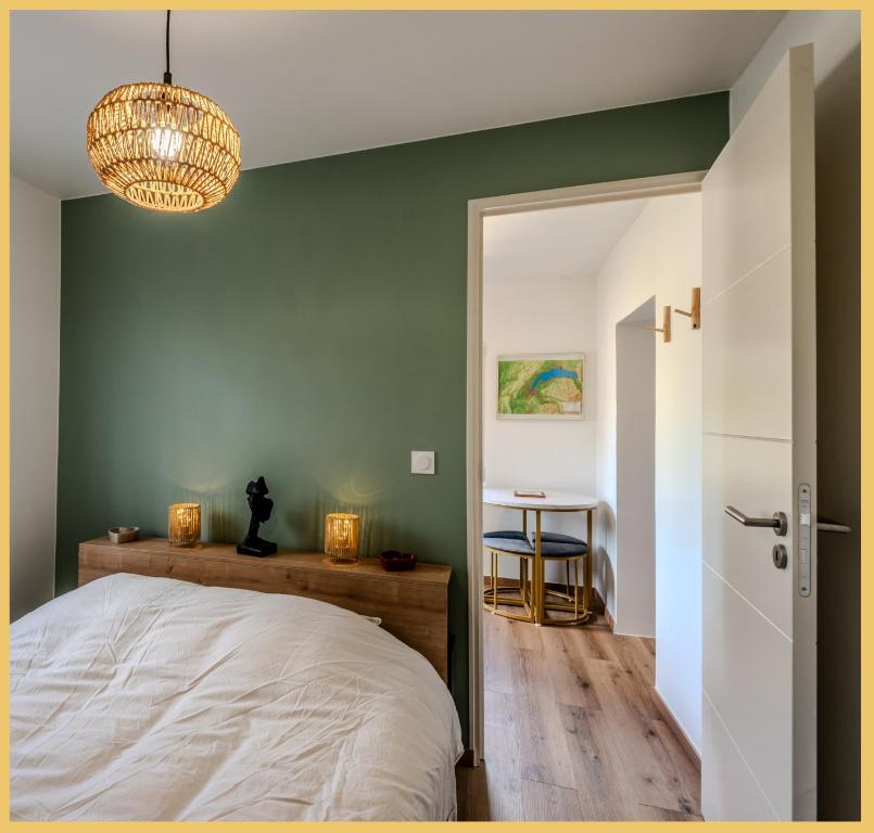 La petite maison de la plage I Excenevex في إكسينيفيكس: غرفة نوم بجدار اخضر فيها سرير وثريا