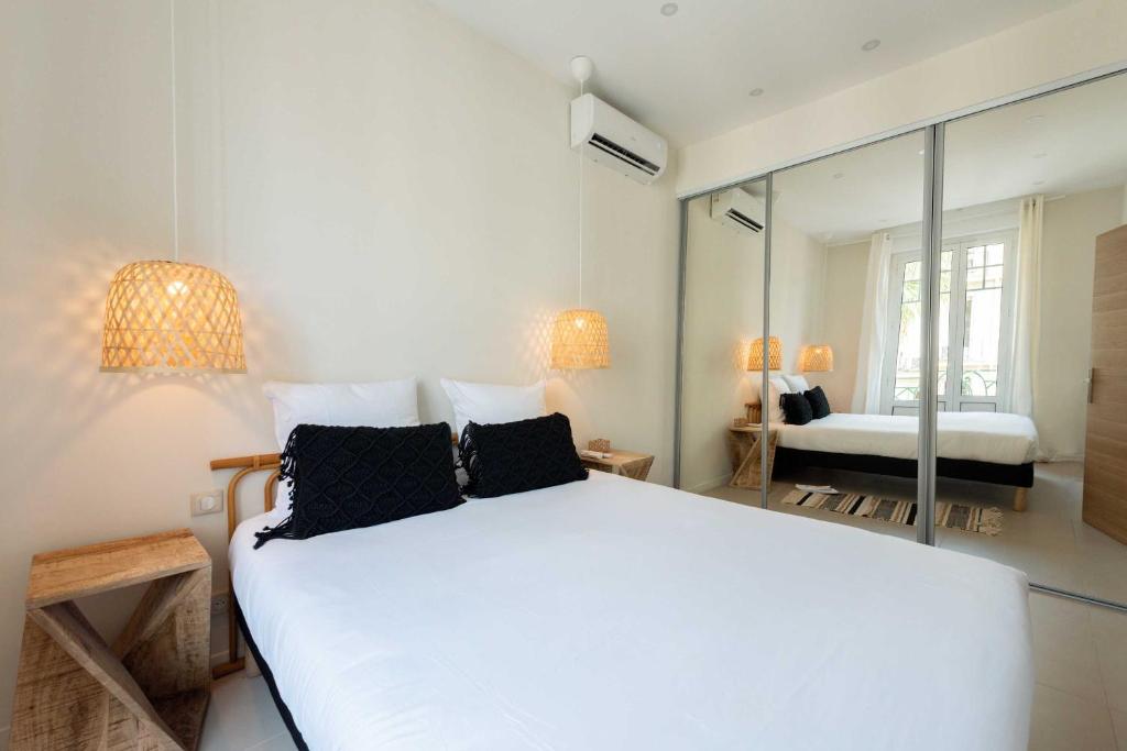 une chambre avec un grand lit blanc et un miroir dans l'établissement Nice apartment Juan-Les-Pins - 300m Beach, à Juan-les-Pins