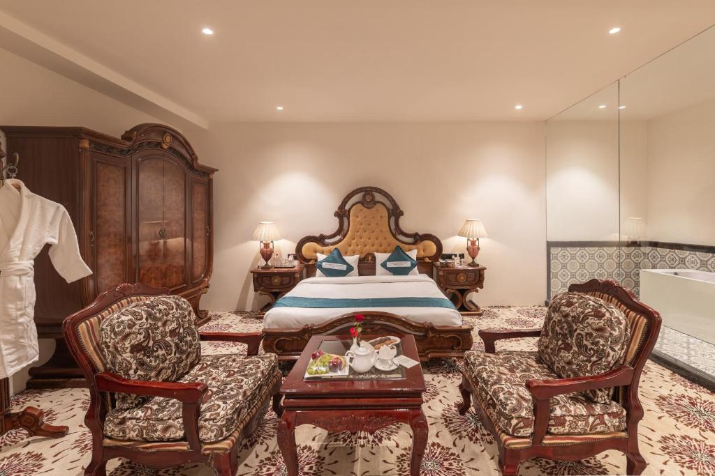阿杰梅尔Clarks Resort The Archi`s Castle, Ajmer的一间卧室配有一张带两把椅子和一张桌子的床。
