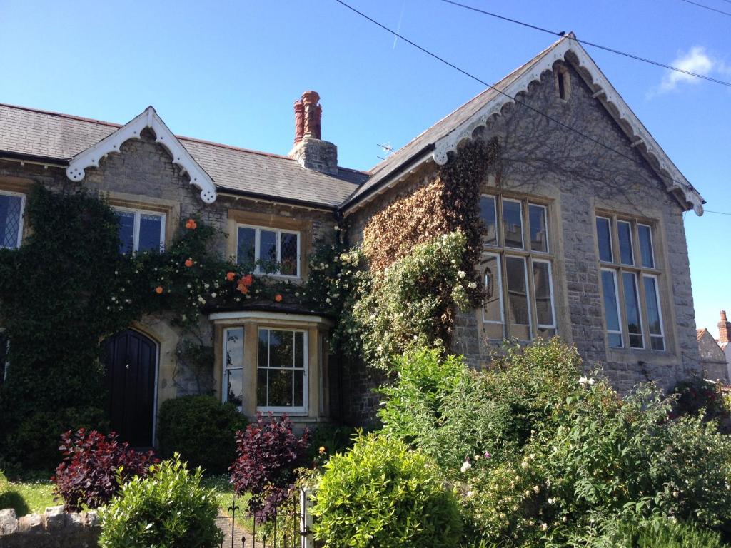 una vieja casa de ladrillo con arbustos delante de ella en The School House, en Bridgwater