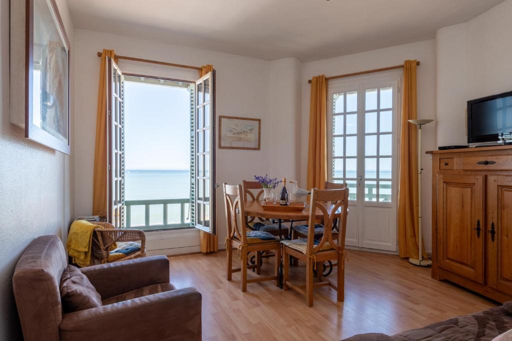 un salon avec une table, des chaises et une télévision dans l'établissement La Falaise - Magnifique Vue Mer, à Mers-les-Bains