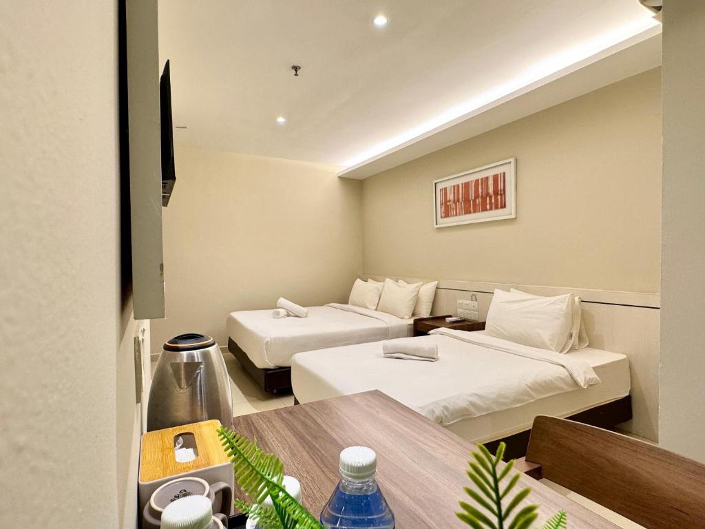 ein Hotelzimmer mit zwei Betten und einem Tisch in der Unterkunft Kingston Hotel 1 - Bukit Bintang in Kuala Lumpur