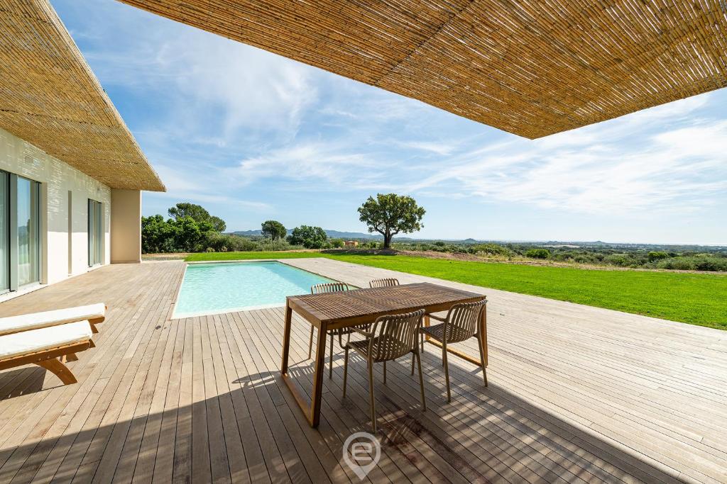 een houten terras met een tafel en stoelen naast een zwembad bij Villa Valentina in Pula