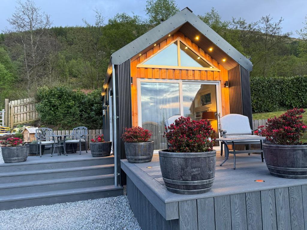 a small house with potted plants on a deck at Tumpseys Hideaway with Hot Tub & Sunset Loch Views, Glencoe Near Fort William in Ballachulish