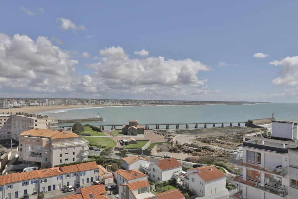 - une vue sur une plage avec des bâtiments et une jetée dans l'établissement Fregates - Vue mer exceptionelle au 12eme etage, à La Chaume