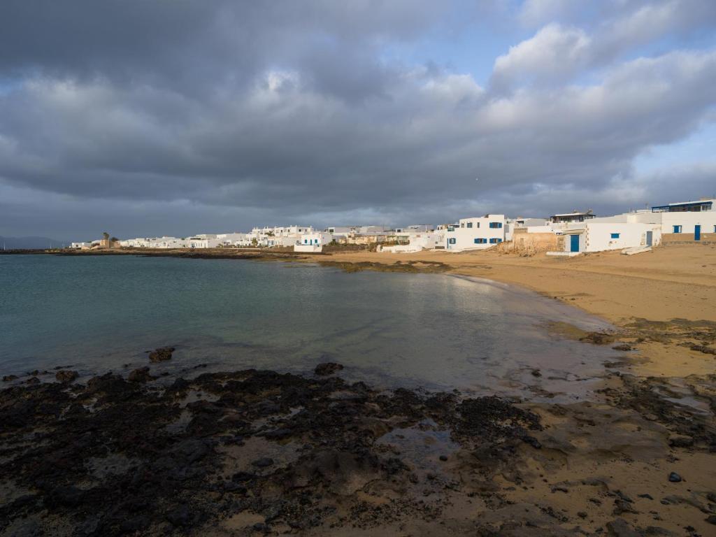 una playa con edificios blancos y agua en La Casa de La Graciosa, en Caleta de Sebo