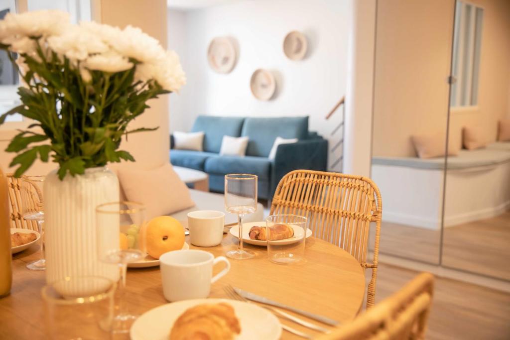 stół z wazonem kwiatów i stół z jedzeniem i napojami w obiekcie Nice 2 bed flat - Hyper centre St Tropez w Saint-Tropez