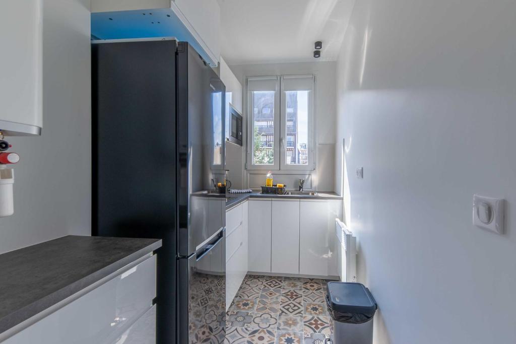 La cuisine est équipée d'un réfrigérateur noir et d'un évier. dans l'établissement Studio sleeps 4 with terrace, 500m Place Morny, à Deauville