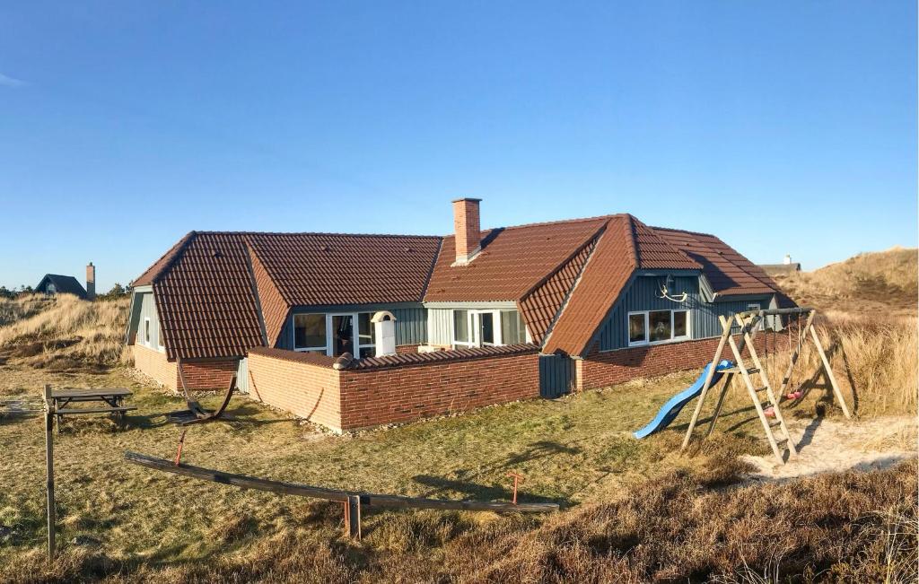 a house on top of a hill with a playground at Cozy Home In Hvide Sande With Sauna in Bjerregård