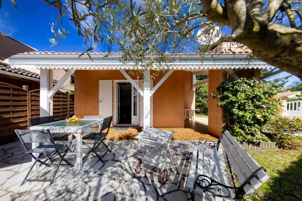 un patio avec une table et des chaises devant une maison dans l'établissement Maisonnette Botticelli - Ares, à Arès