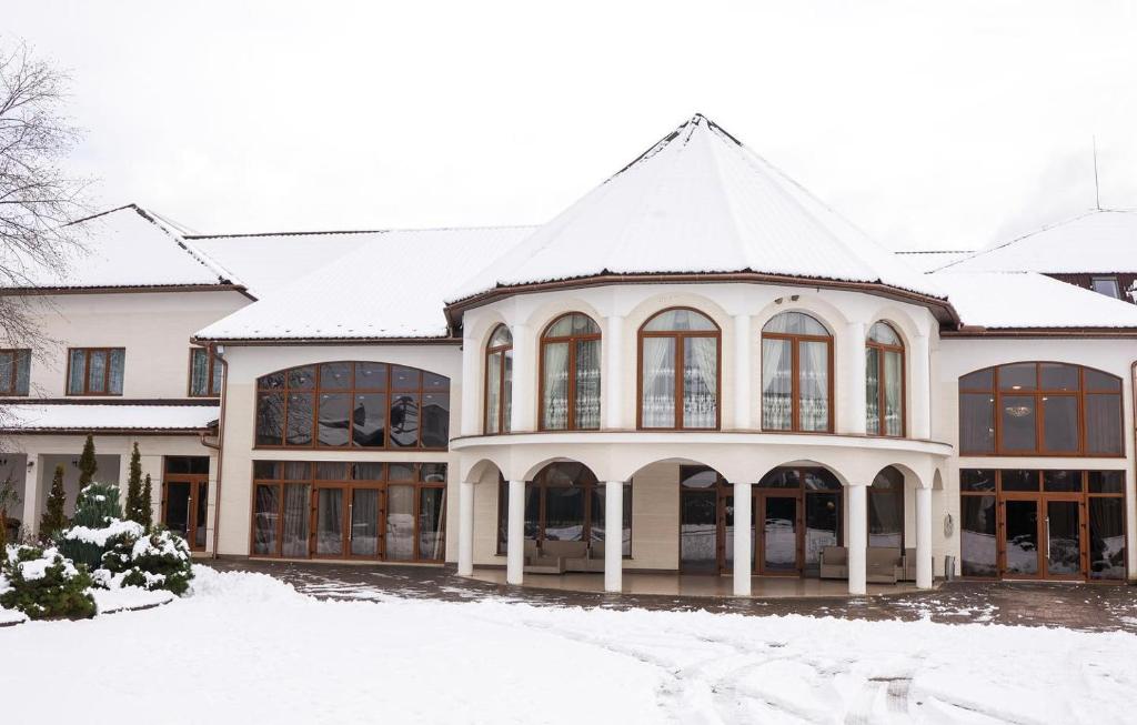 Hotel Stas في Irshava: مبنى أبيض كبير مغطى بالثلوج على الأرض