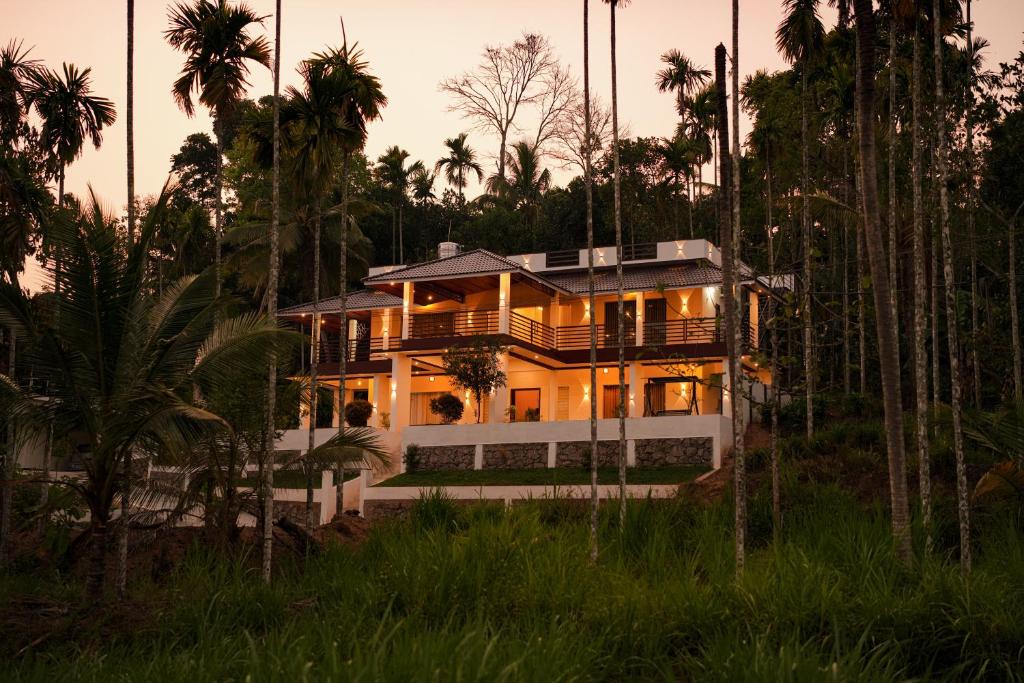 a house in the middle of a forest with palm trees at The Calm County Homestay in Mānantoddy