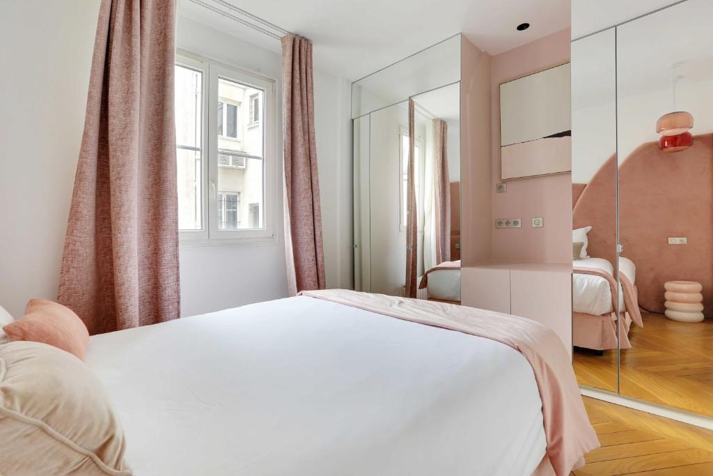 une chambre avec un lit blanc et un miroir dans l'établissement Appartement Élégant & Spacieux - 3BR-6P - Républiq, à Paris