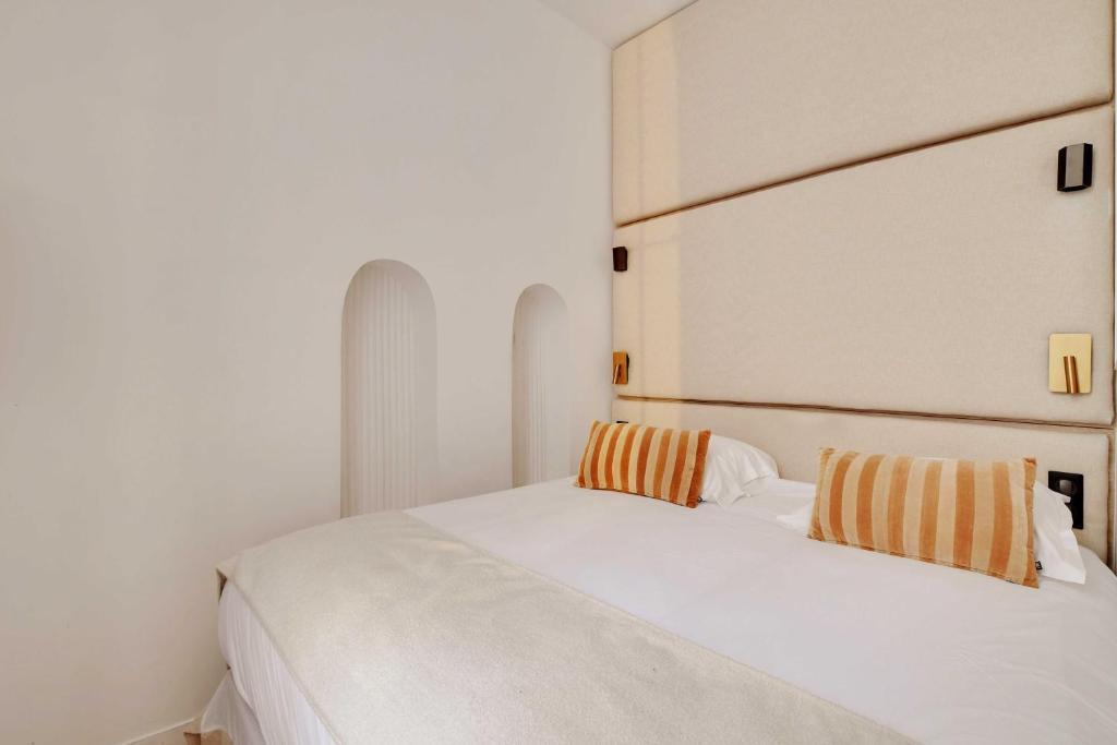 un lit blanc avec deux oreillers orange et blancs dessus dans l'établissement Welcoming apartment - 1BR-4P - Sentier, à Paris