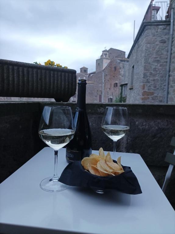 a table with a bottle of wine and two glasses at Sospesi nel borgo in Vitorchiano