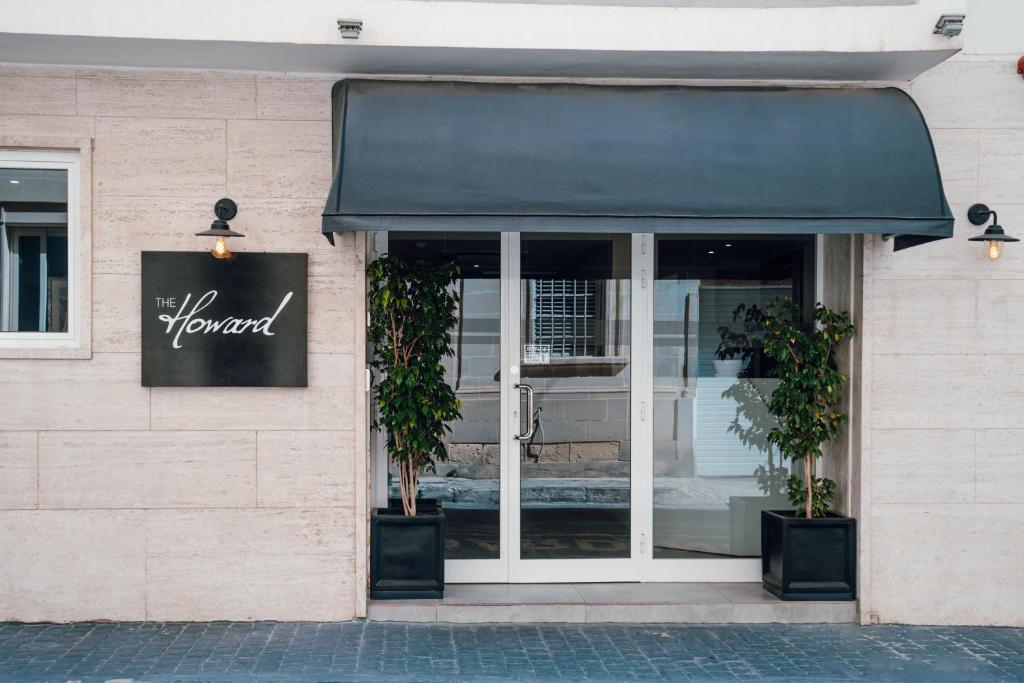 a store front with a black awning and two plants at The Howard Hotel in Sliema