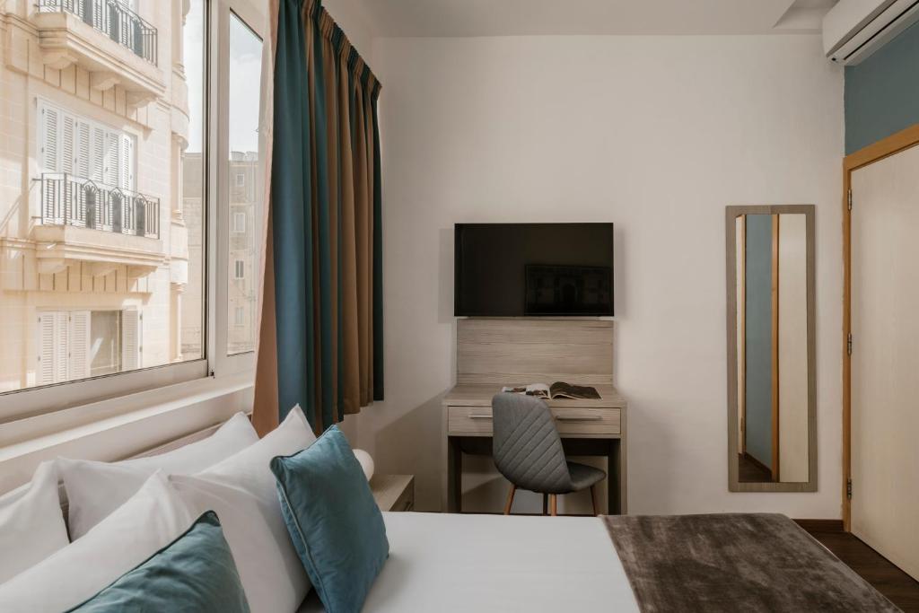 a hotel room with a bed and a desk at The Howard Hotel in Sliema