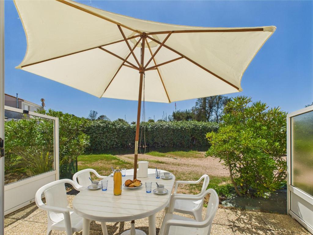 une table et des chaises blanches avec un parasol dans l'établissement Appartement pour 4 - Terrasse - 100m du Port, à Saint-Hilaire-de-Talmont