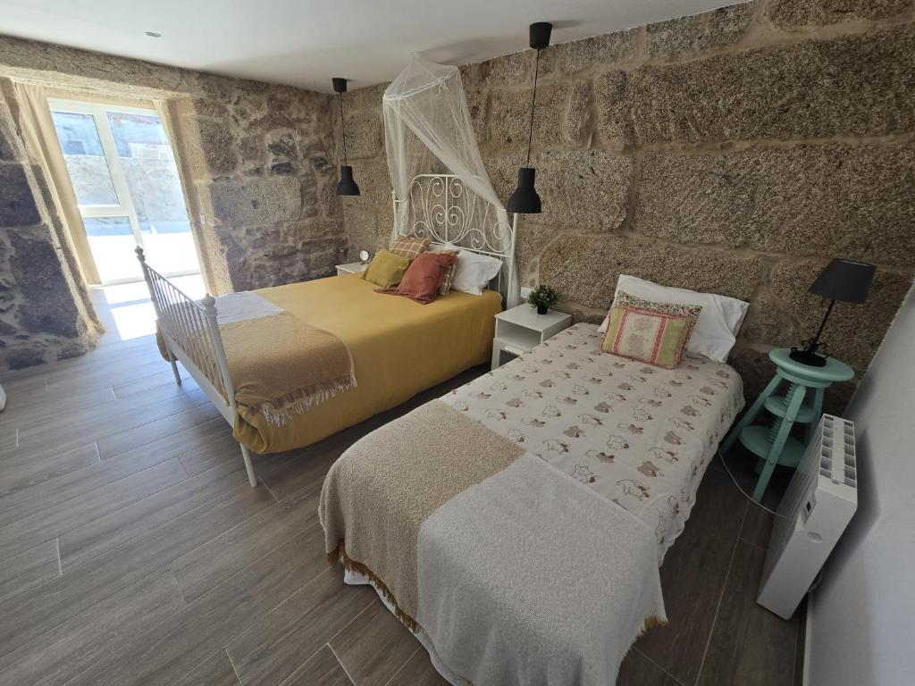 a bedroom with two beds and a stone wall at CASITA RECIEN HABILITADA A ESTRENAR CON PISCINA EN MALVAS Tuy in Malvas