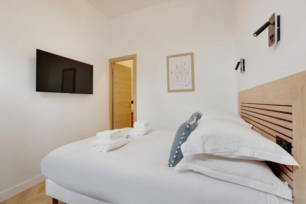 - une chambre blanche avec un lit et une télévision murale dans l'établissement Superbe appartement - 2BR-6P - Bastille, à Paris