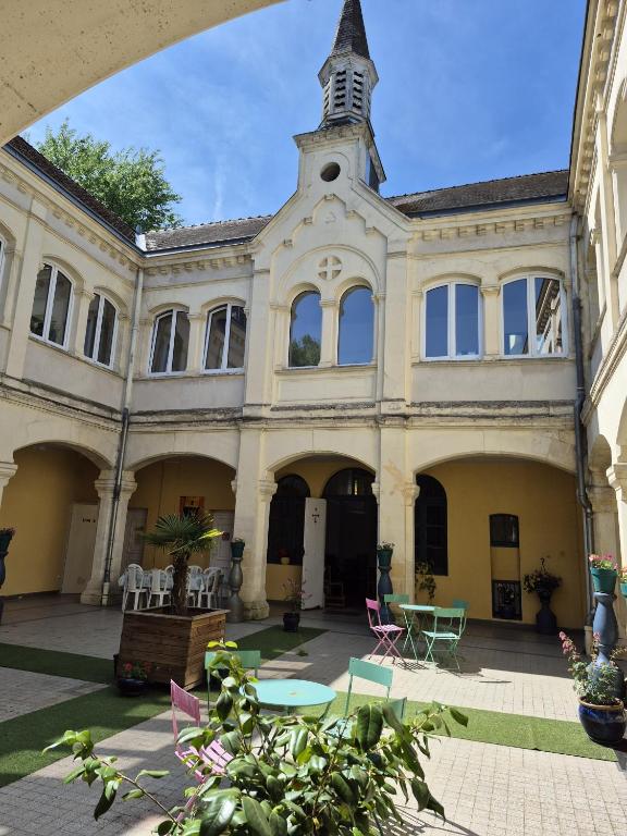 un grand bâtiment avec une tour d'horloge au sommet dans l'établissement Motel le Bon Samaritain, à Roucy