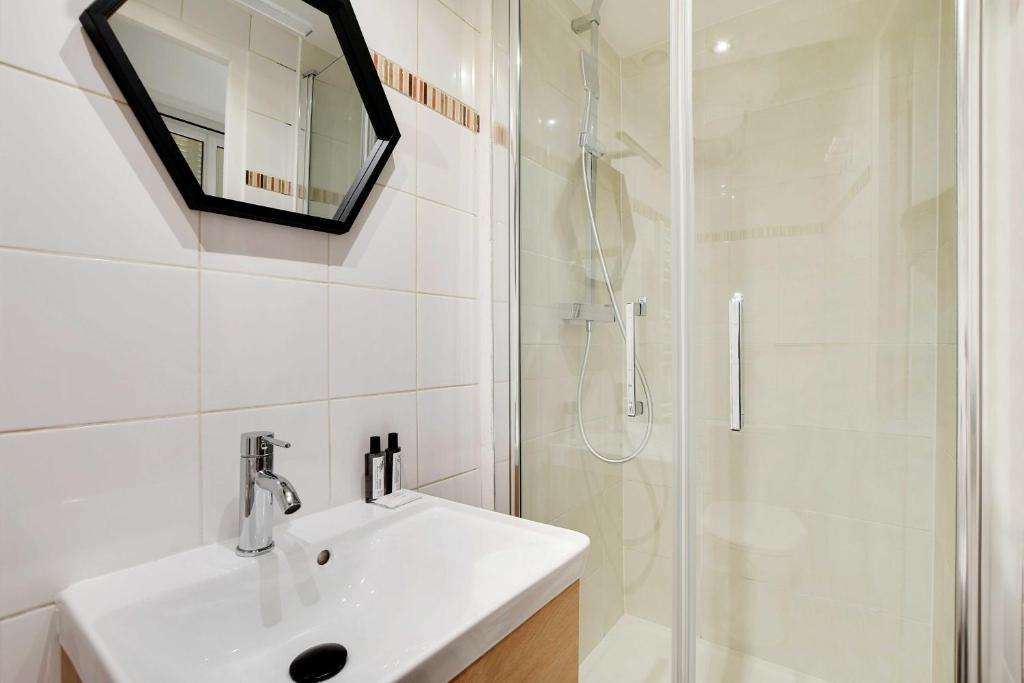 une salle de bain blanche avec un lavabo et une douche dans l'établissement Peaceful studio - 2P - Buttes-Chaumont with AC, à Paris