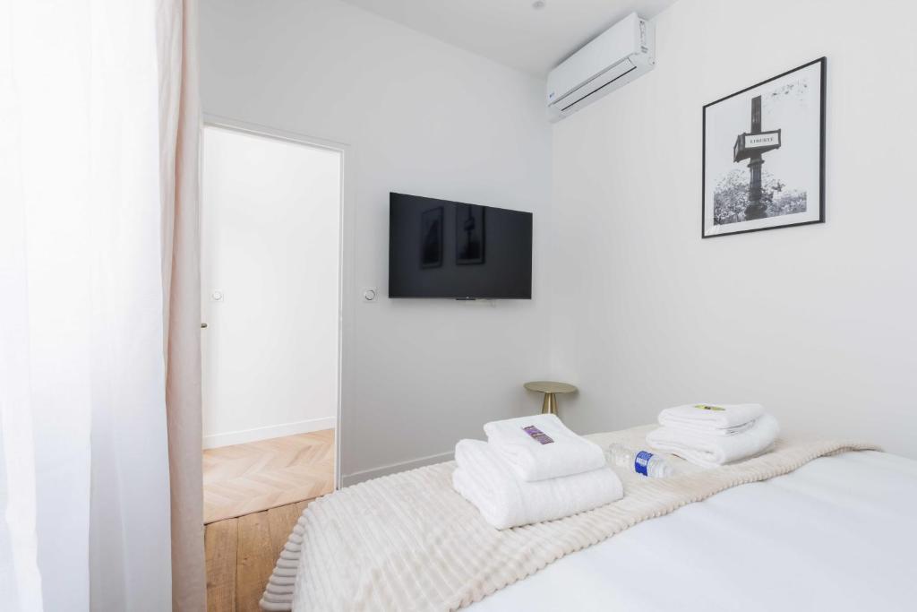 une chambre blanche avec un lit et un miroir dans l'établissement Charmant Appartement 2BR-6P - Gare de l'Est, à Paris
