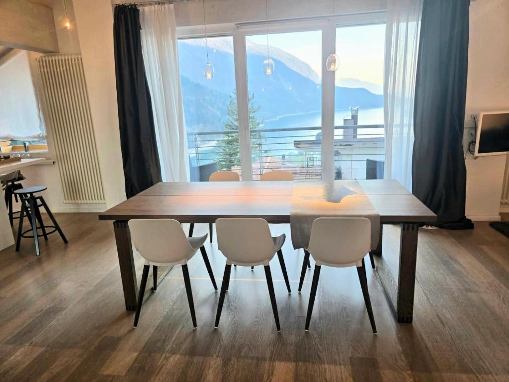 a dining room table with chairs and a large window at Alpin Lake Haven in Molveno