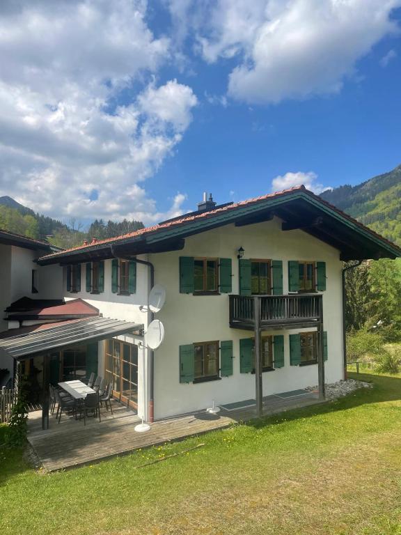 a large white house with a patio and a table at Landhaus Maiergschwendt inkl Chiemgaukarte in Ruhpolding