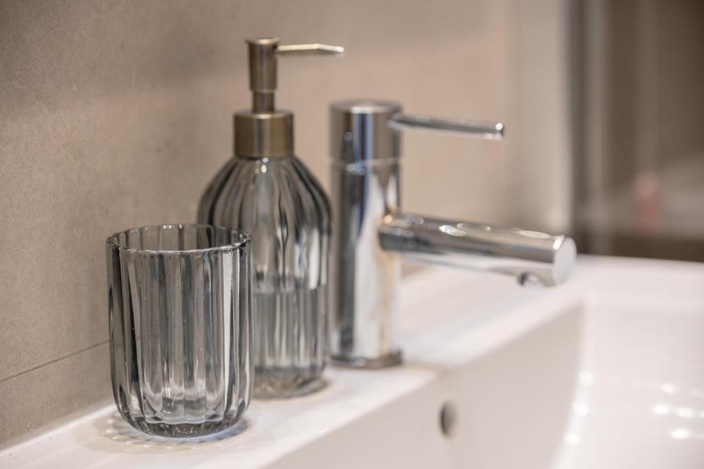 a bathroom sink with a soap dispenser and a glass cup at Via Santa Croce 1 in Milan