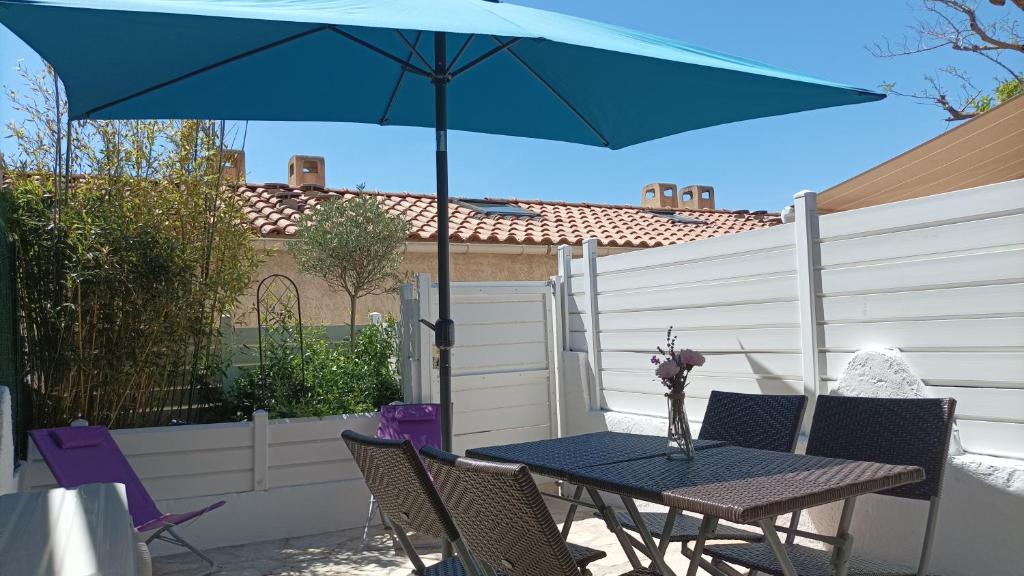 - une table avec un parasol bleu sur la terrasse dans l'établissement Villa club, à Sanary-sur-Mer