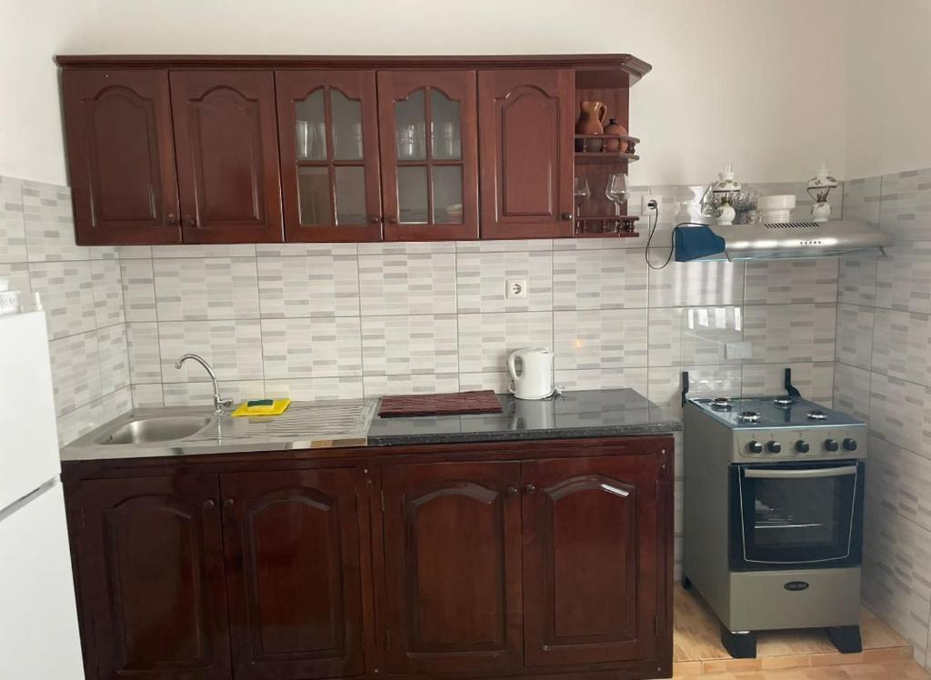 een keuken met houten kasten en een fornuis bij 1 chambre proche aeroporto cabo verde in Espargos