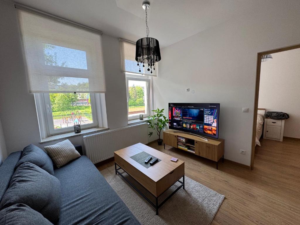 a living room with a blue couch and a tv at Apartment between the bridges in Zgorzelec