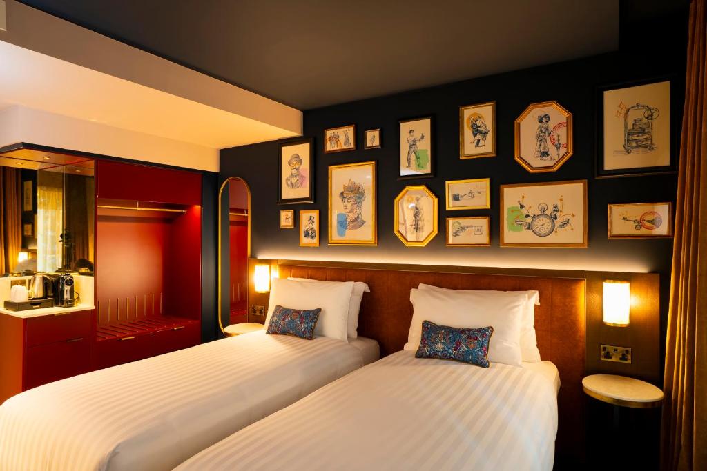 two beds in a room with pictures on the wall at The Mercantile Hotel in Dublin