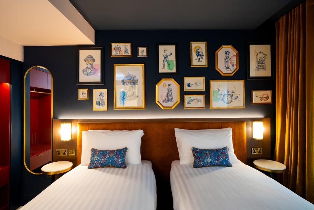 two beds in a room with pictures on the wall at The Mercantile Hotel in Dublin
