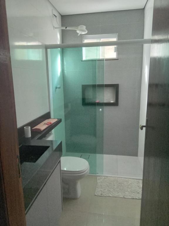 a bathroom with a toilet and a glass shower at Casa de alto padrão in Macacos