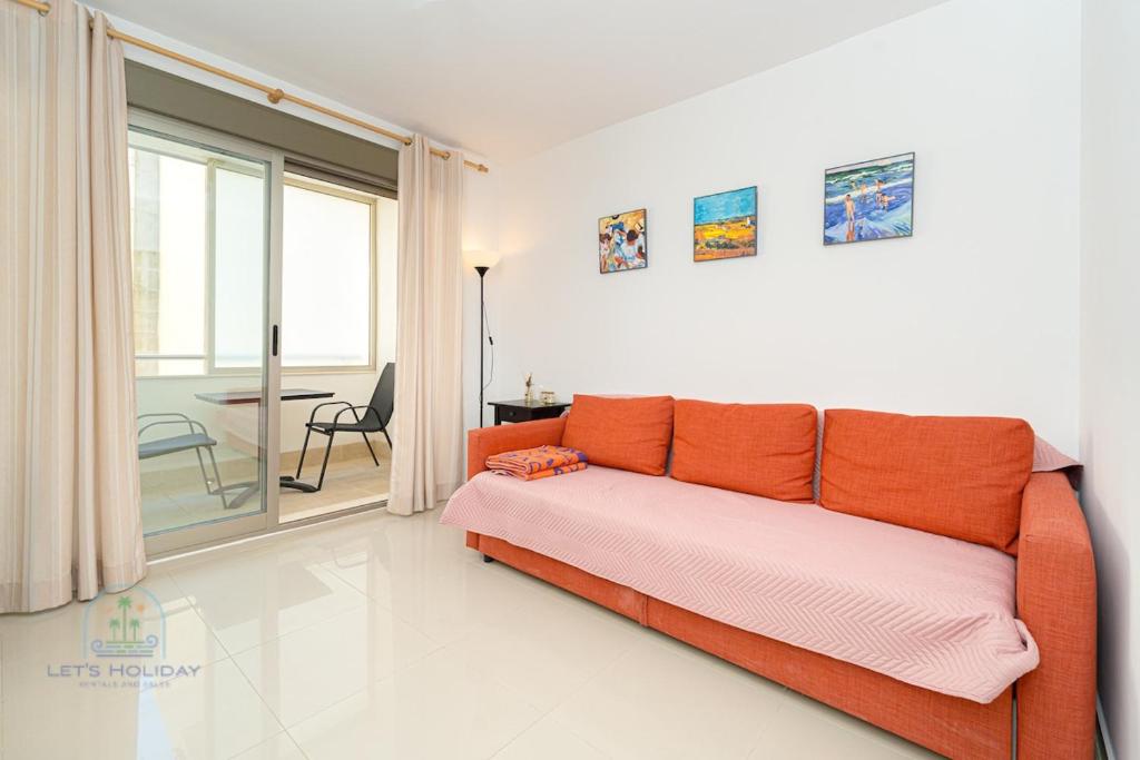 an orange couch in a white room with a table at 1 Bed Apartment with pool La Red in El Campello