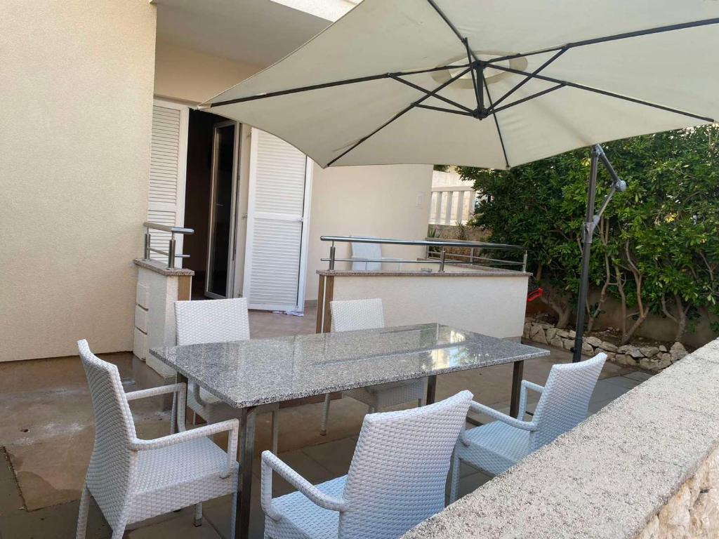 a table and chairs with an umbrella on a patio at Apartment IB Studio Pag6 in Kustići