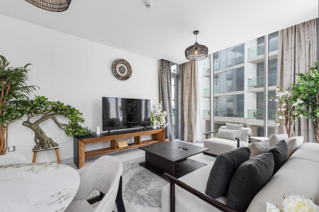 ein Wohnzimmer mit Sofa und Fernseher in der Unterkunft Luxurious 1 BR in District One Beach Access in Dubai