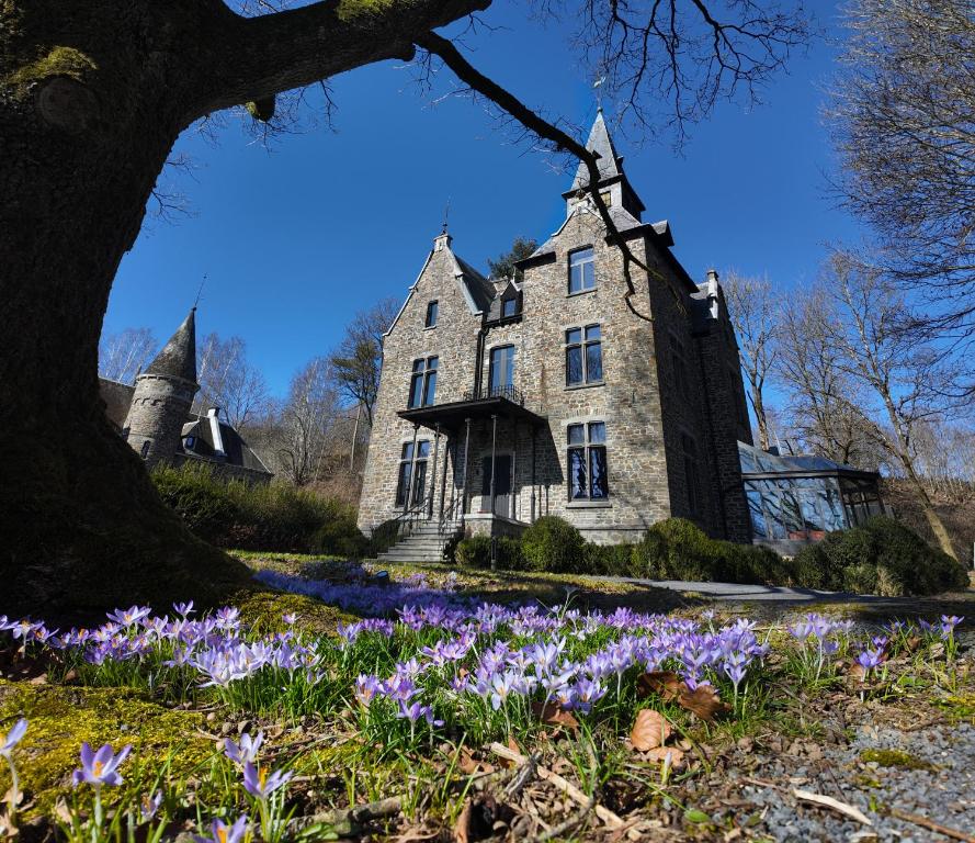 an old house with purple flowers in front of it at Châteaux de Méliris in Tenneville