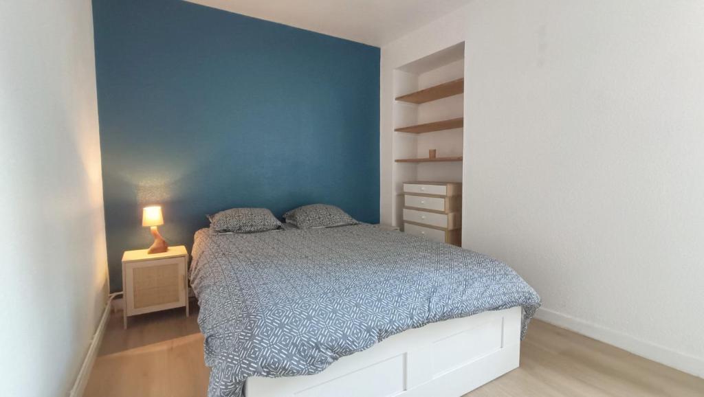 une chambre avec un lit et un mur bleu dans l'établissement Maison cosy avec jardin – Centre de Poitiers, à Poitiers