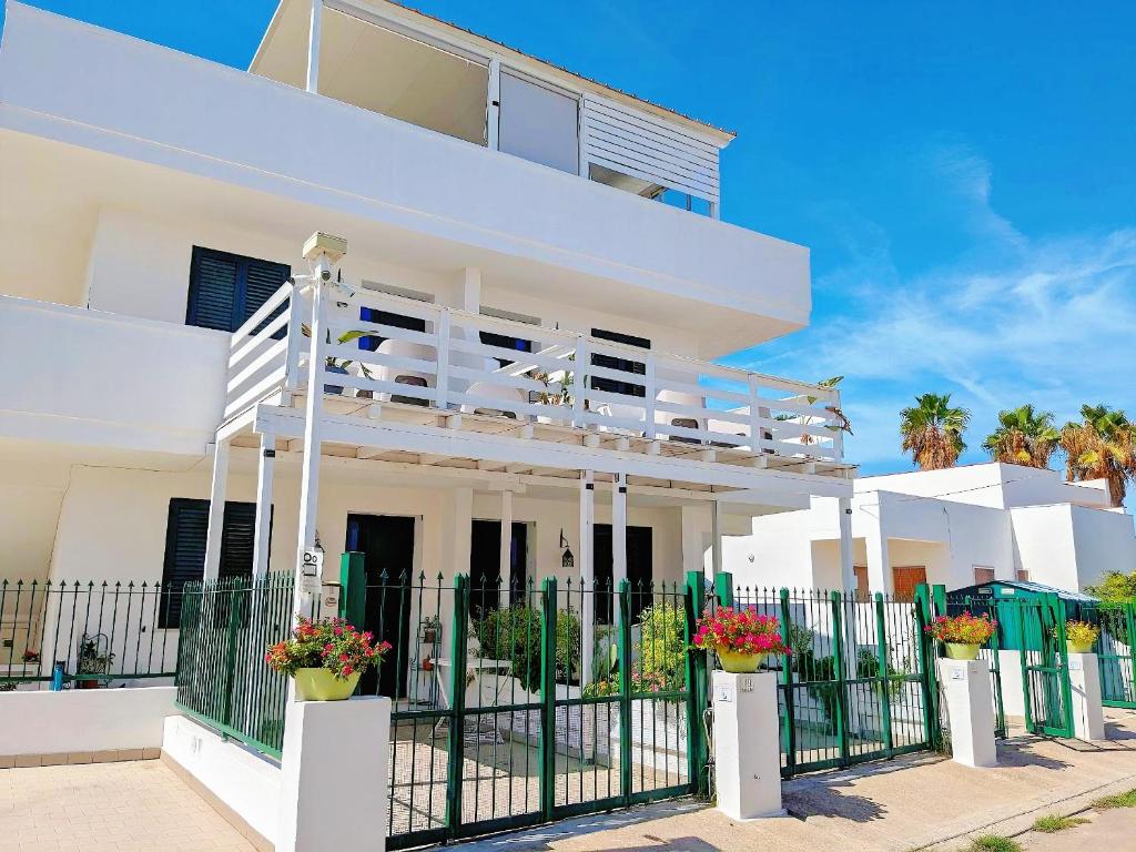 a white house with a balcony and a fence at B&B Casa De Mare in Lido Marini
